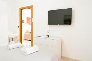 a white bedroom with a tv on a wall at Levante Eight Appartamento Vista Mare in Bari