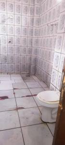 Un baño con inodoro y una pared de azulejos. en Casa da Família Nascimento, en Ananindeua