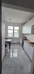 a kitchen with white cabinets and a table in it at Apartament 2 pokojowy z widokiem na morze in Sarbinowo