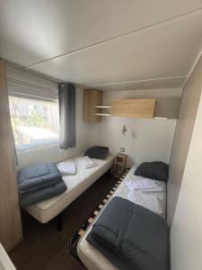 a small room with two beds and a window at Mobil home 6 à 8 personnes in Piriac-sur-Mer +26 photos
