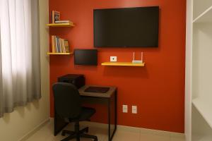 a desk with a chair and a television on a wall at Apartamento Cantinho da Cop 30 in Ananindeua