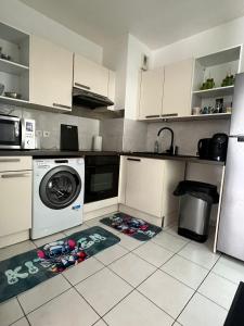 a kitchen with a washing machine on the floor at appartement 5min gare RER Disneyland Paris val d'Europe la vallée Village parking inclus in Montévrain