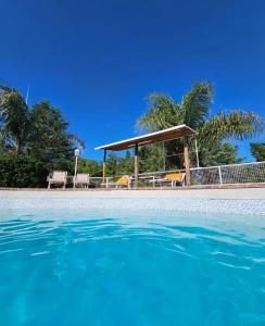 a swimming pool with a gazebo and the water at Complejo Lago Chico in Tanti