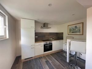 a kitchen with white cabinets and a sink and a stove at Ferienwohnungen am Roland in Neustadt