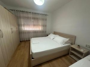 Un dormitorio pequeño con una cama blanca y una ventana. en Lenci's Apartment, en Berat