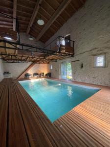 a large swimming pool in a large room with a ceiling at Suites zen dans maison d'hôtes avec piscine intérieure et jardin in Ventenac-Cabardès