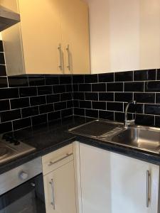 a kitchen with white cabinets and a sink and black tiles at The Tudor House Hotel in Nottingham