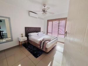 a bedroom with a bed and a ceiling fan at Tranquil Shores Modern 1BR WiFi Pool Beach in Richards Bay