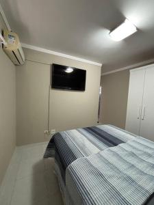 a bedroom with a bed and a tv on the wall at Apartamento enseada Guarujá in Guarujá