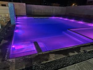 a pool with purple lights on it at night at Marechal Plaza Hotel in São Gabriel +144 photos