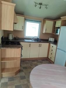a small kitchen with white cabinets and a window at Comfy caravan in Eyemouth in Eyemouth +10 photos