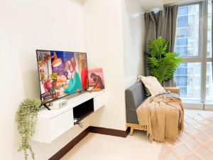 Una sala de estar con un televisor de pantalla plana en una pared. en Stylish 1BR Prime BGC Uptown near Hyatt #upt119c, en Manila