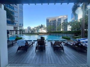 una persona sentada en una terraza junto a una piscina en Stylish 1BR Prime BGC Uptown near Hyatt #upt119c, en Manila