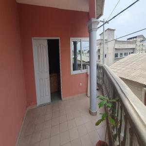 a balcony of a red house with a white door at Appartement meublé à Fidjrossè Cotonou in Cotonou