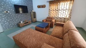 a living room with a couch and a tv at Appartement meublé à Fidjrossè Cotonou in Cotonou
