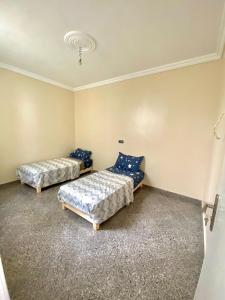 two beds in a room with blue pillows at Dar el baraka in Ras El Ma