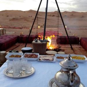 una mesa con comida en el desierto en TRIP Merzouga luxury camp, en Adrouine