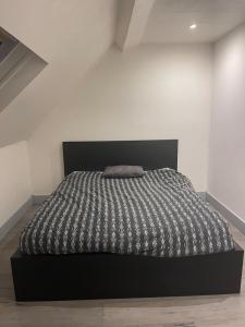 a bedroom with a black bed with a black headboard at Appartement refait à neuf en centre ville in Bonneuil-sur-Marne +1 photo