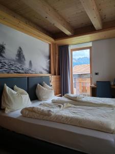a bedroom with two beds and a large window at Al Sole B&B Valcomelico in Santo Stefano di Cadore