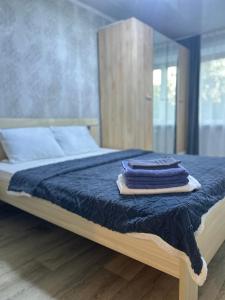a bed with three blue towels on top of it at УЮТ 2-комнатная квартира в центре in Petropavlovsk