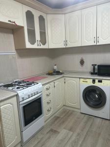 a kitchen with a stove and a washing machine at УЮТ 2-комнатная квартира в центре in Petropavlovsk