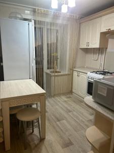 a kitchen with white cabinets and a table and a stove at УЮТ 2-комнатная квартира в центре in Petropavlovsk +3 photos