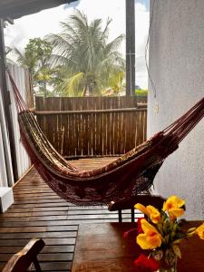 a hammock on a balcony with a palm tree at Casa Brisa Noronha in Fernando de Noronha
