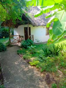 una casa con techo de paja y un camino delante en The Makuti breeze house, en Mtwapa