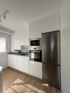 a kitchen with white cabinets and a stainless steel refrigerator at Apartamento García in Nerja +7 photos
