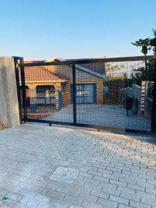a fence in front of a house with a building at Ha-Dzibs backpackers accommodation in Thohoyandou