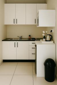 a white kitchen with a sink and white cabinets at 46 On Aries Studio Apartment in Northwold +5 photos