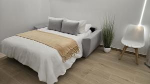 een slaapkamer met een bed en een stoel en een plant bij Padul Suites Apartamentos in Padul +21 foto's