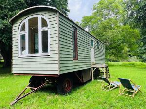 a tiny house sitting on a truck with two chairs at HAEVN Bauwagen Marienfliess in Meyenburg