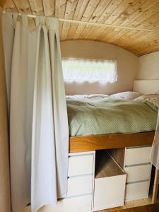 a bed in a tiny house with a window at HAEVN Bauwagen Marienfliess in Meyenburg