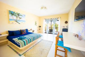 a bedroom with a blue bed and a kitchen at Atenea 3 private bedrooms in Holbox Island