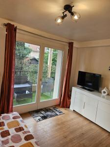 a bedroom with a television and a sliding glass door at Chambre avec salon et balcon - Gare Annemasse in Annemasse