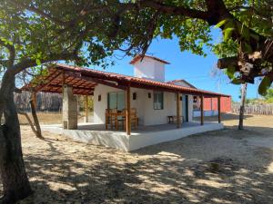 a small white house with a red roof at Suite Sol - Quarto e Banheiro com Ar Condicionado in Luis Correia