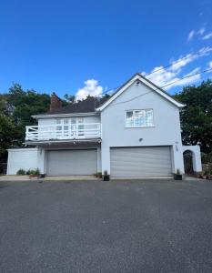 a white house with two garage doors at Lovely 2-Bedroom New Forest apartment on a Farm in New Milton