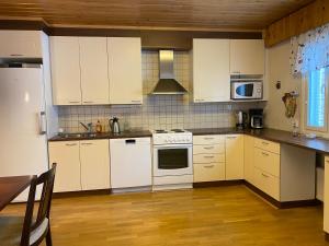 a kitchen with white appliances and a wooden floor at Dream Big House Tervaharju in Kemi