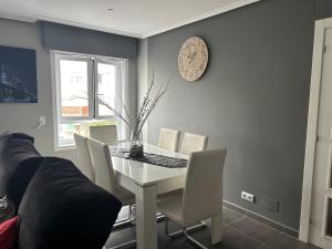 ein Esszimmer mit einem Tisch und einer Uhr an der Wand in der Unterkunft Apartamento en Cedeira in Cedeira + 6 Fotos