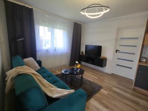 a living room with a blue couch and a table at Apartament Anny in Grodzisk Mazowiecki