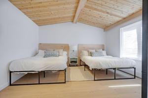 two beds in a room with white walls and wooden ceilings at Rockway Motel in Saint-Rémi-dʼAmherst