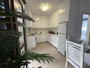 Una cocina con gabinetes blancos y un refrigerador blanco. en Modern 2BR Apartment 70m from Finikoudes beach, en Lárnaca