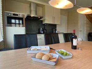 a table with two trays of food and a bottle of wine at Luxe vakantiewoning met stoomcabine en bubbelbad in Tzummarum