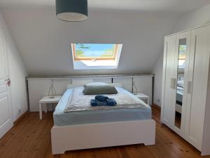 a white bedroom with a bed and a window at St Jacques in Port-Bail-sur-Mer