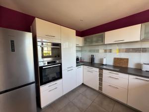 a large kitchen with white cabinets and appliances at St Jacques in Port-Bail-sur-Mer