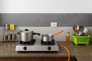 two pots and pans on a stove in a kitchen at Radha Rachna Apartment in Vrindāvan