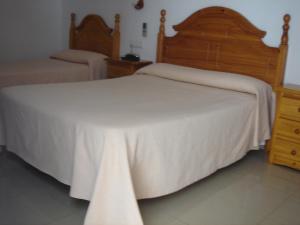 a bedroom with two beds with white sheets and a dresser at Hostal Toscano in San Juan del Puerto