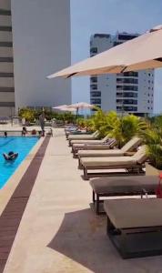 a row of chaise lounges and umbrellas next to a pool at Cartagena Beach Resort cerca al aereopuerto in Cartagena de Indias