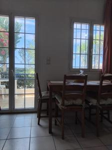 a dining room with a table and chairs and windows at Angelo's Apt in Mesochórion +8 photos